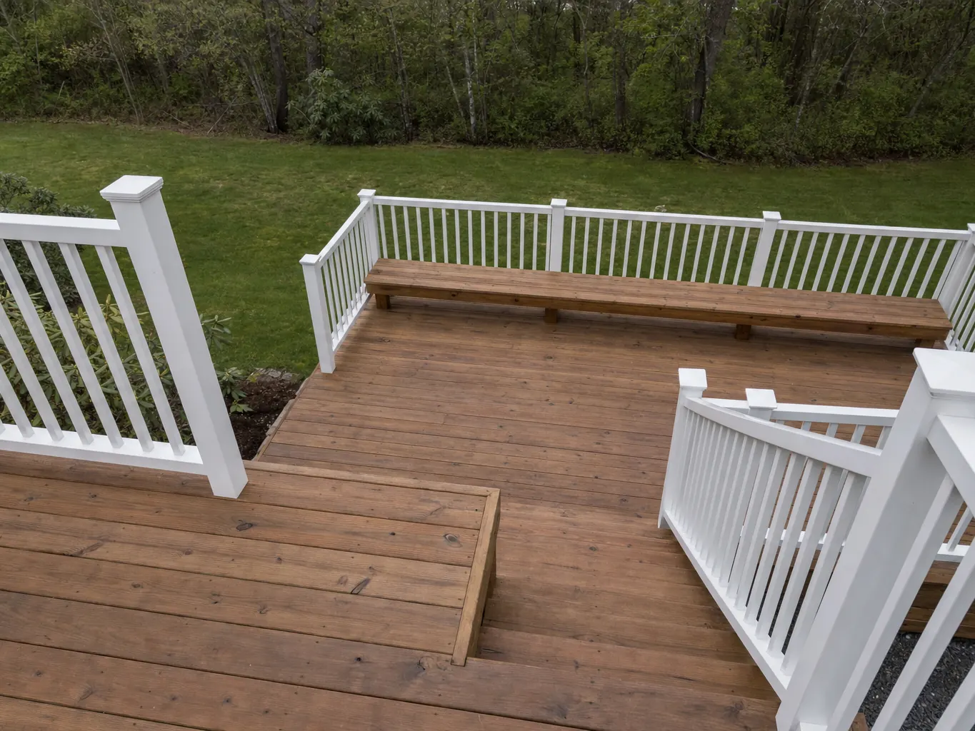 Multi level deck with white railings and a built in bench