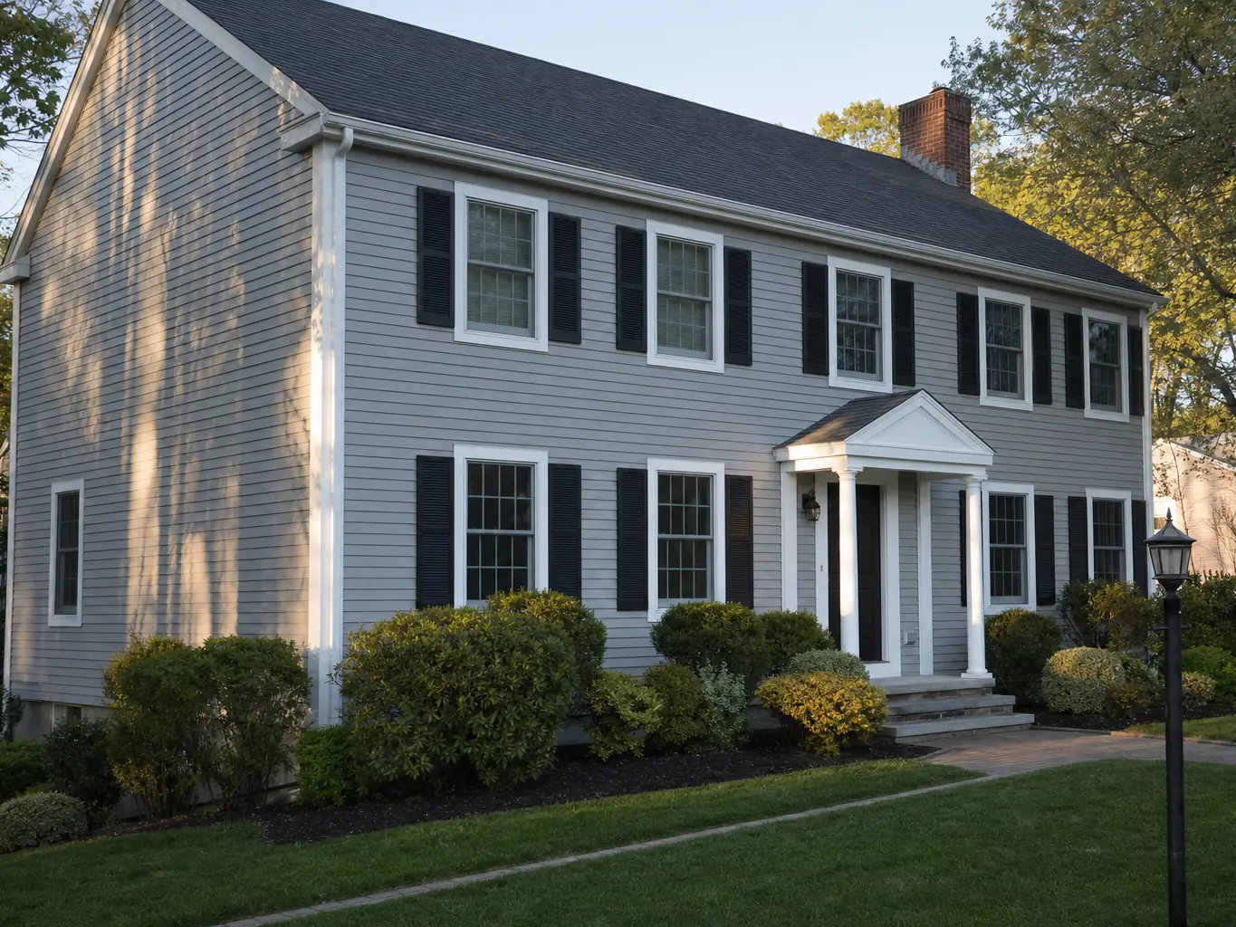 Two story colonial with new light grey siding and black shutters