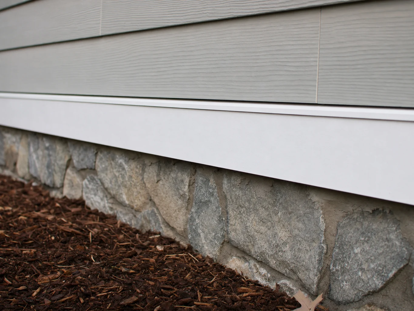 Water table trim where new siding meets the stone foundation