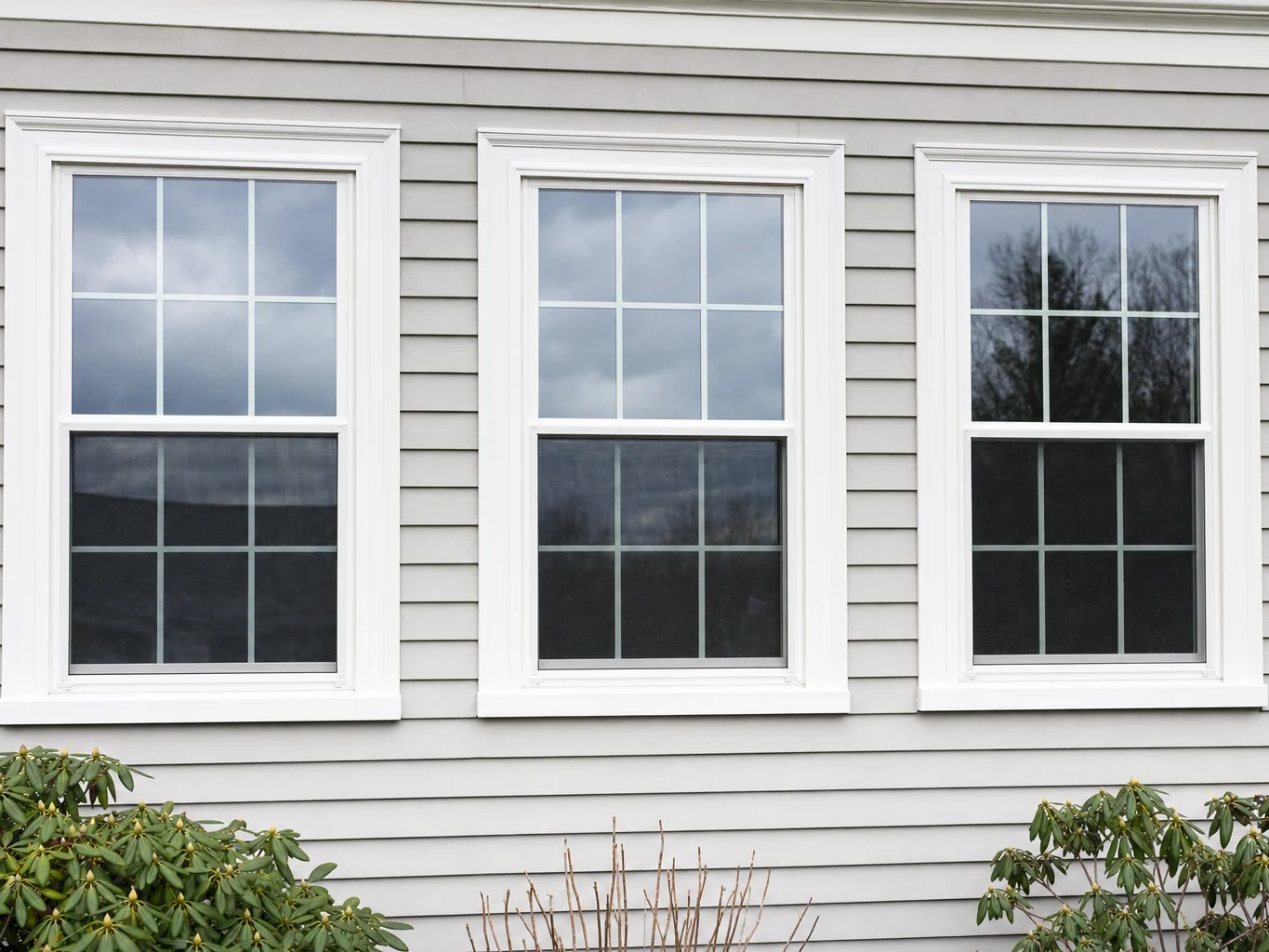 Three new white double hung windows with fresh exterior casing